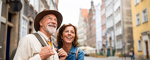 © Halfpoint - AdobeStock.com Lächelndes älteres Paar erkundet gemeinsam eine historische Altstadtstraße