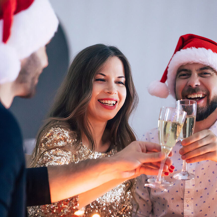 © Maksym Provozniuk - AdobeStock.com Fröhliche Weihnachtsfeier mit Freunden, Sekt und festlich gedecktem Tisch