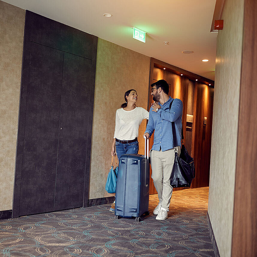© luckybusiness - AdobeStock.com Paar mit Koffern im Hotelflur freut sich auf den Aufenthalt im Maritim Hotel