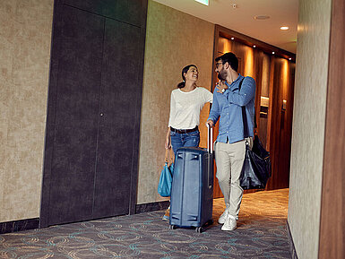 © luckybusiness - AdobeStock.com Paar mit Koffern im Hotelflur freut sich auf den Aufenthalt im Maritim Hotel