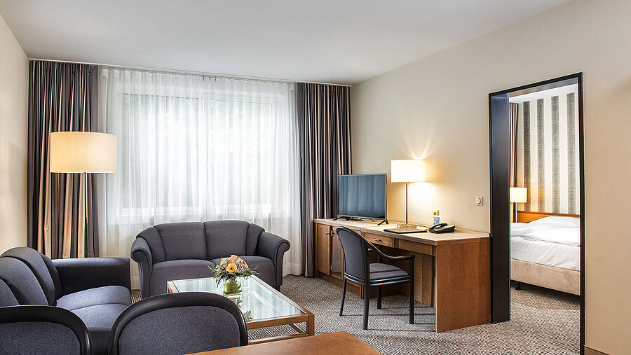 Junior Suite Wohnbereich mit Sofas, TV, Schreibtisch und Blick ins Schlafzimmer im Maritim Hotel Stuttgart
