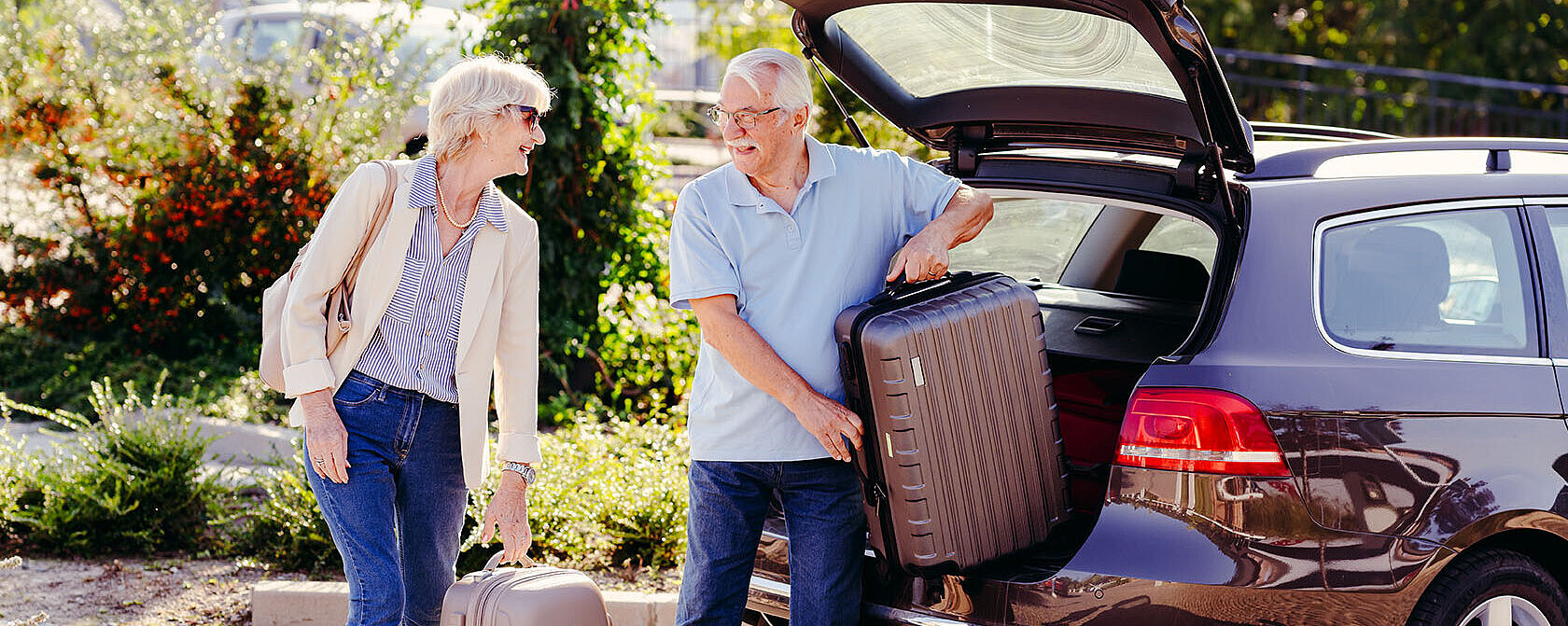 © lordn AdobeStock.com Älteres Paar lädt Koffer aus dem Kofferraum eines Autos und bereitet sich auf eine Reise vor.