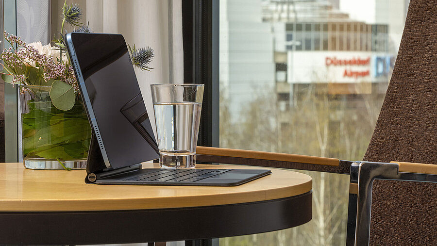 Classic Zimmer Detailaufnahme eines Tisches im Maritim Hotel Düsseldorf mit Tablet, Glas Wasser und Blick auf den Flughafen Düsseldorf.