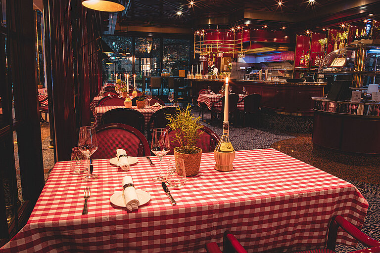 Restaurant Brasserie Gemütlich gedeckter Restauranttisch mit Kerze und rotem Karomuster am Abend
