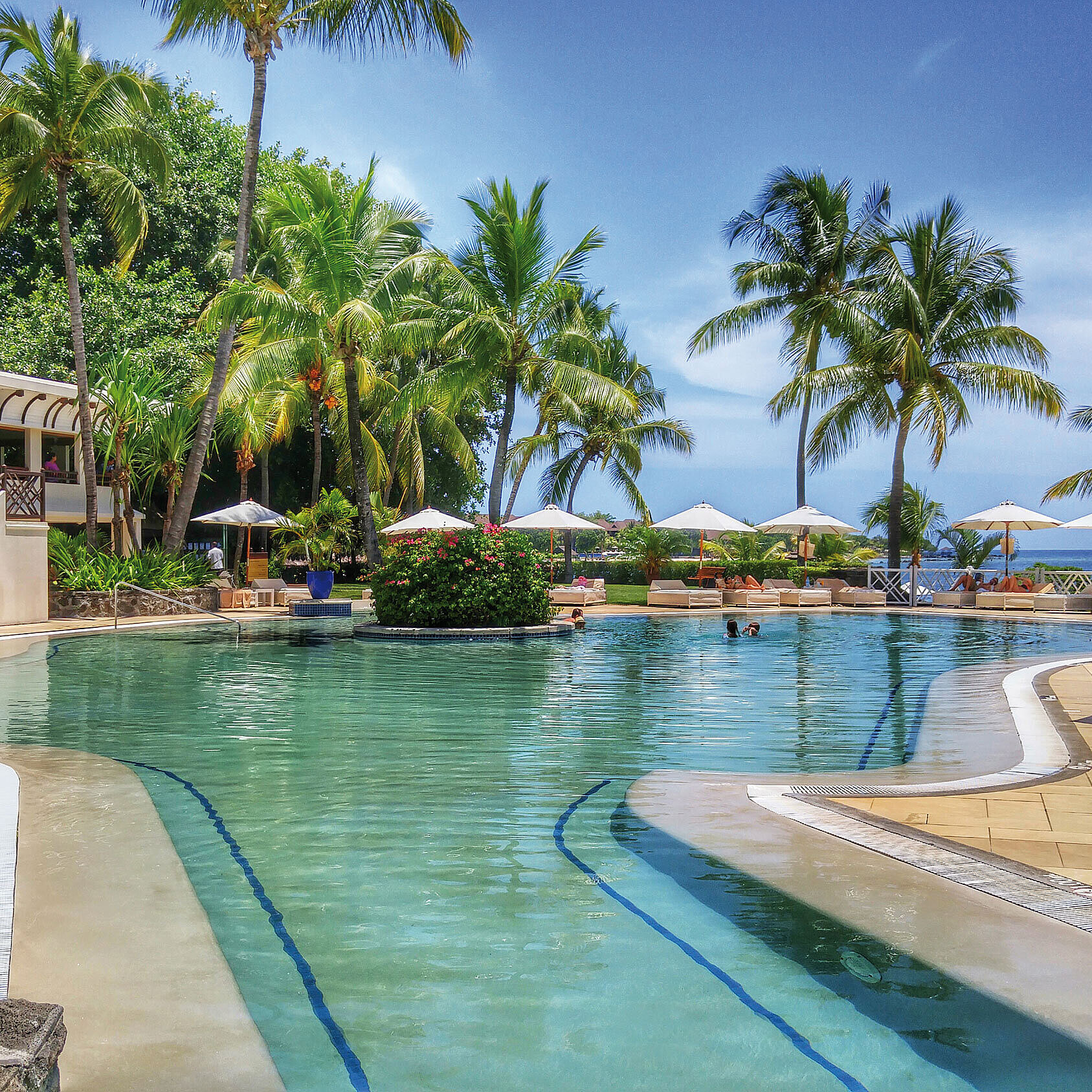 Pool Großer Hotelpool mit Palmen, Sonnenliegen und Meerblick in tropischer Urlaubsatmosphäre