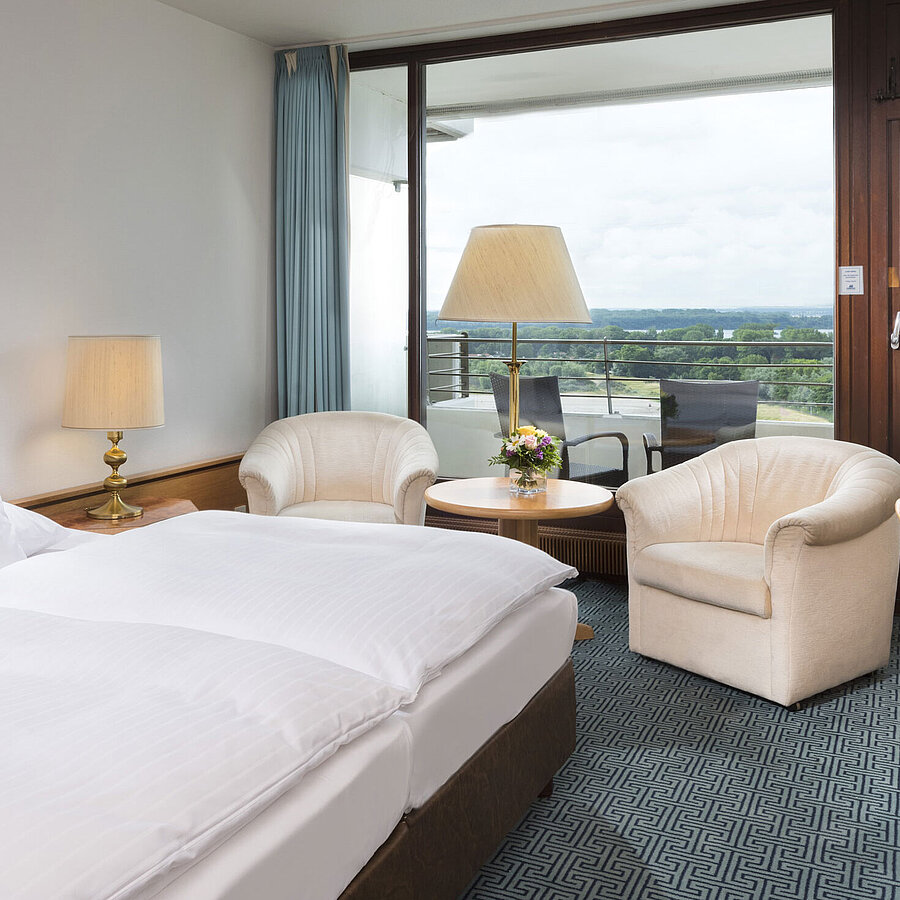 ComfortPlus Zimmer  Doppelzimmer mit Sitzgruppe, Schreibtisch und Balkon mit Ausblick auf grüne Landschaft in Travemünde