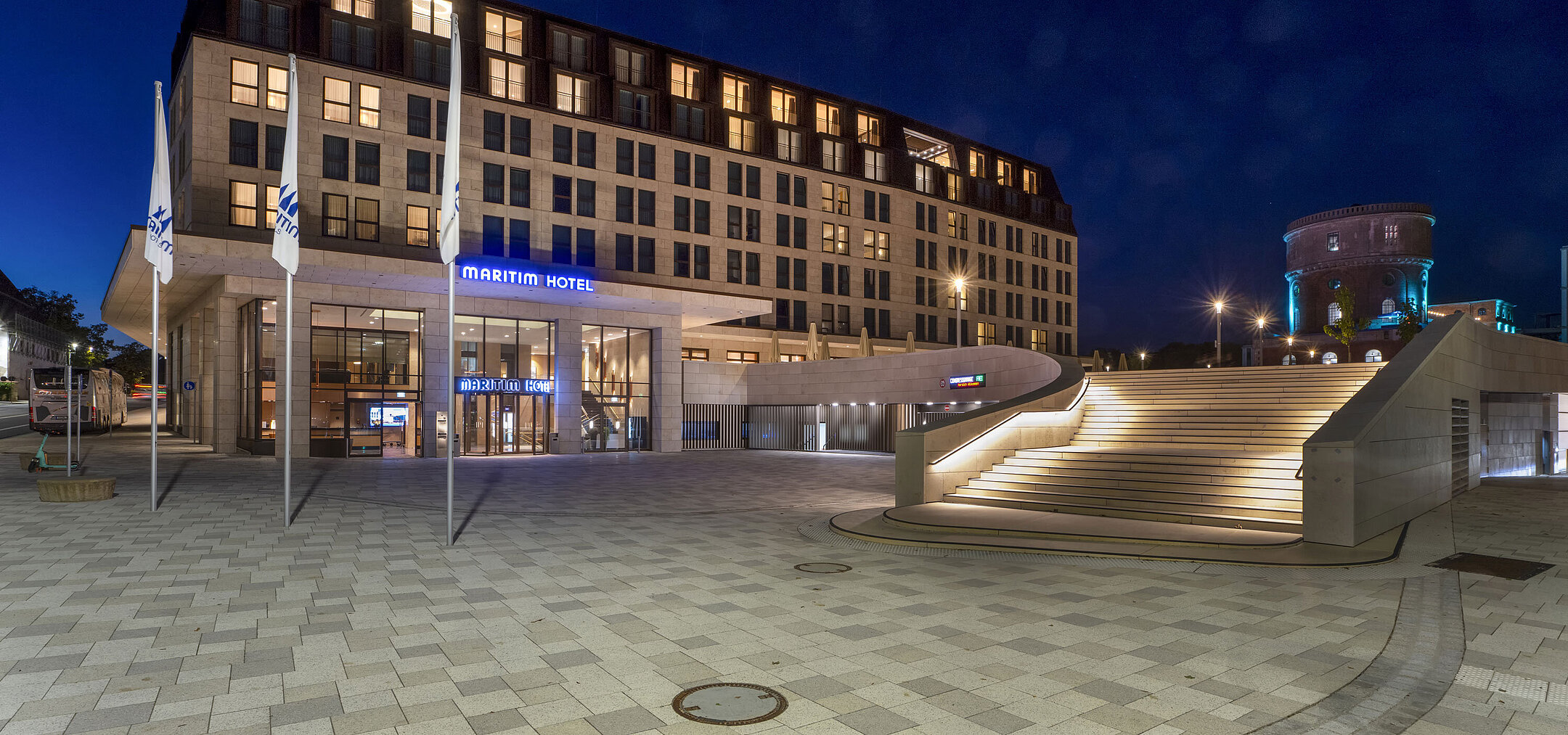 Außenansicht Eingangsbereich des Maritim Hotel Ingolstadt bei Nacht mit stimmungsvoller Beleuchtung und Treppe.