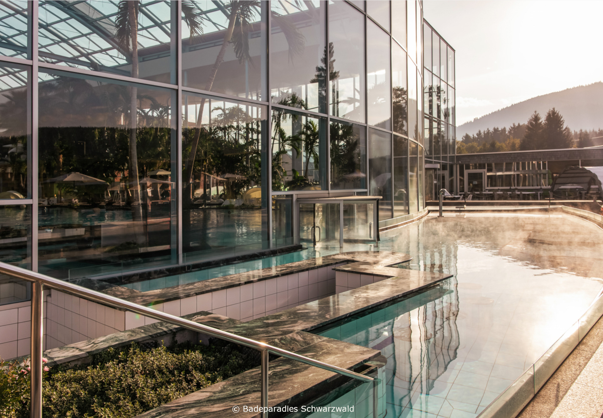 Palmenoase © Badeparadies Schwarzwald Modernes Spa-Gebäude mit Außenpool und Wasserbecken bei Sonnenuntergang