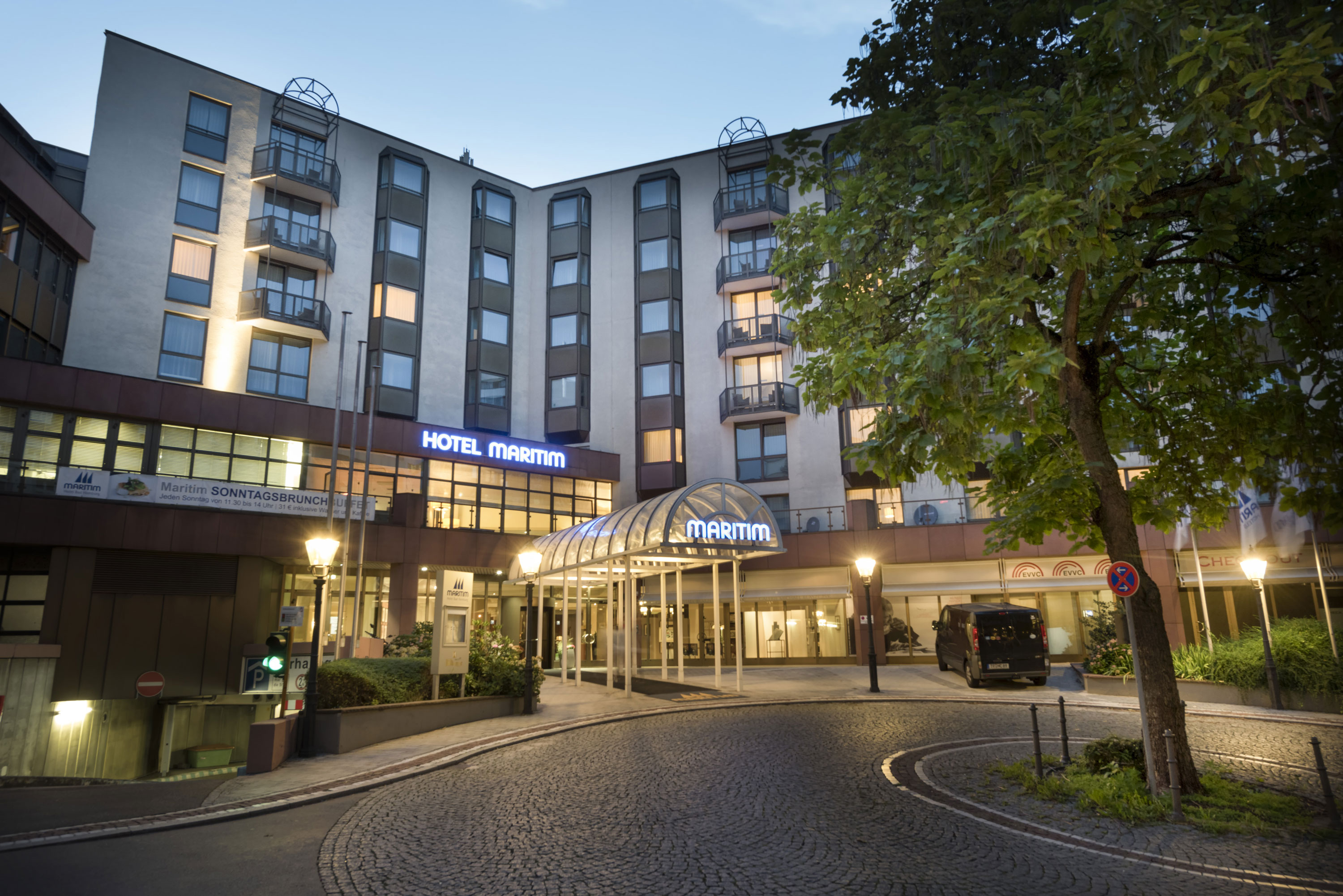Außenansicht bei Nacht Stimmungsvoller Hoteleingang des Maritim Hotel Bad Homburg in der Abenddämmerung mit Beleuchtung.