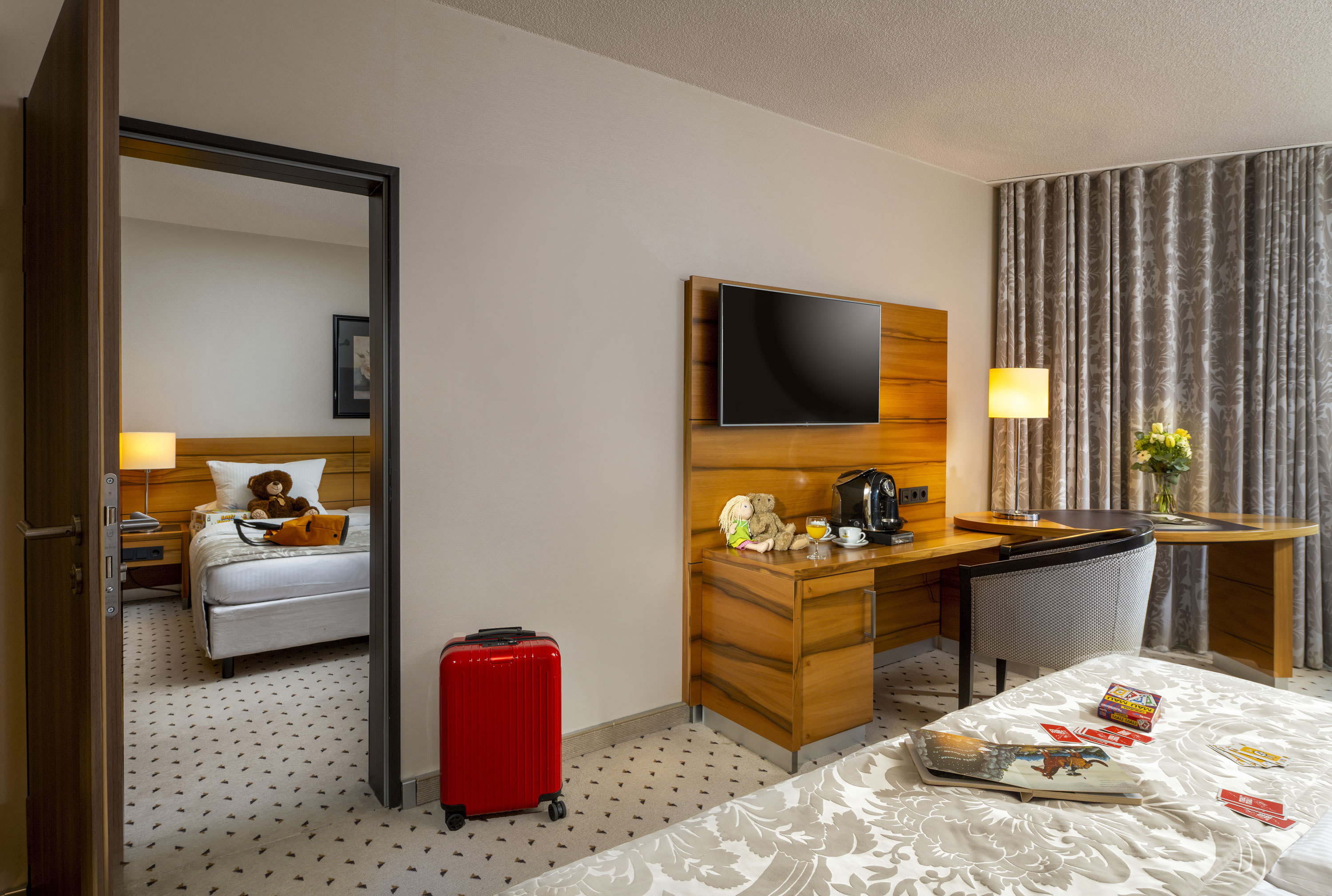 Comfort Familienzimmer Familienzimmer im Maritim Hotel Bad Homburg mit getrenntem Kinderzimmer, Kuscheltieren und roten Koffer.