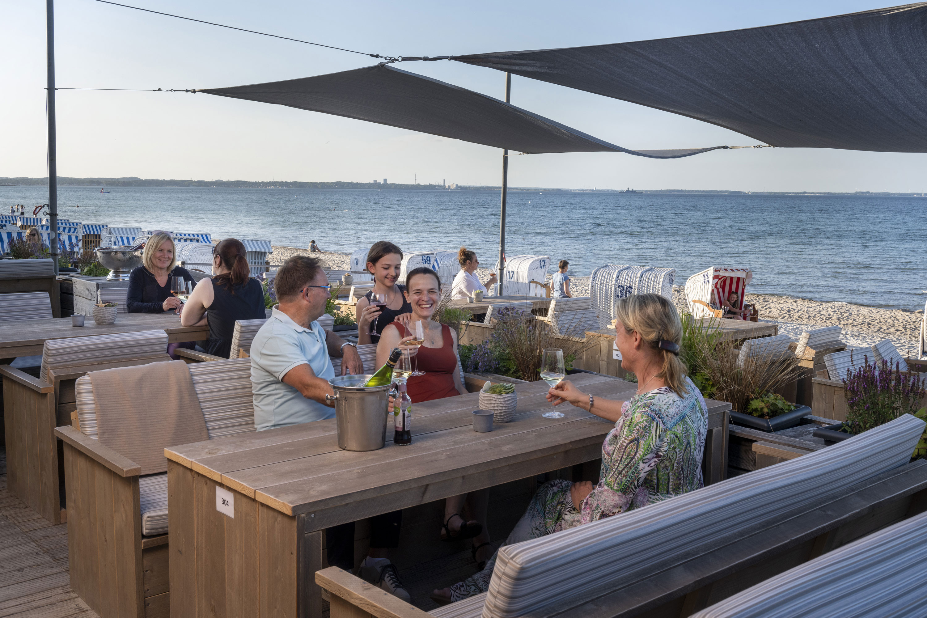 Beach Lounge Gruppe von Gästen in der Strandbar des Maritim Seehotel Timmendorfer Strand, genießt Drinks mit Meerblick und Strandkörben.