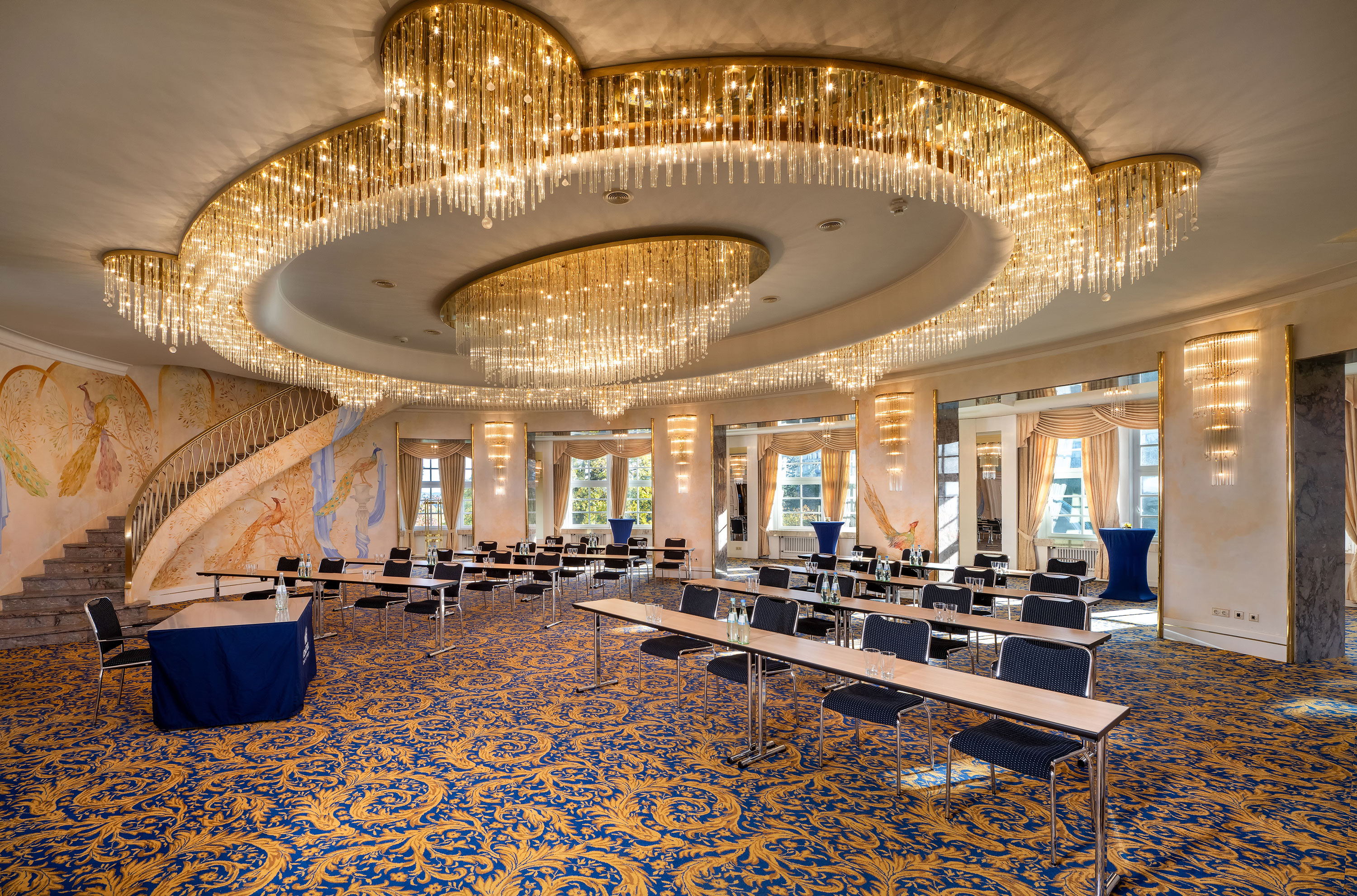 Fürst-von-Pückler-Saal Fürst-von-Pückler-Saal mit großer Fensterfront, Reihenbestuhlung, markanten Deckenleuchten und hellem Ambiente.