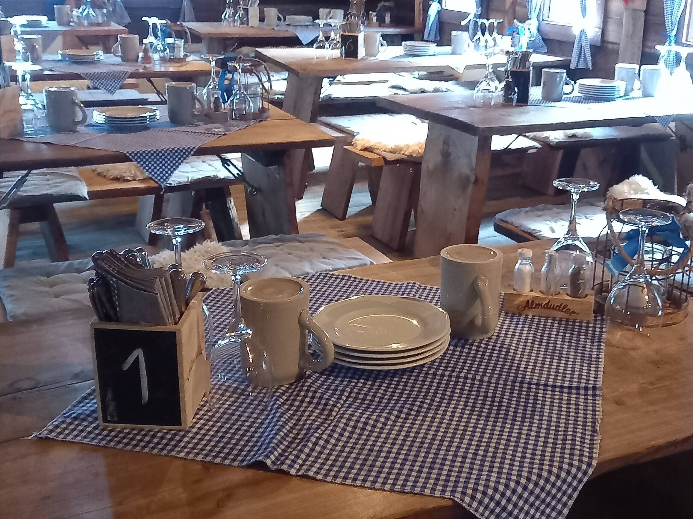 Maritim Alm (innen) Lange Holztische mit Geschirr und karierten Tischdecken in der Maritim Alm beim Maritim Hotel Stuttgart