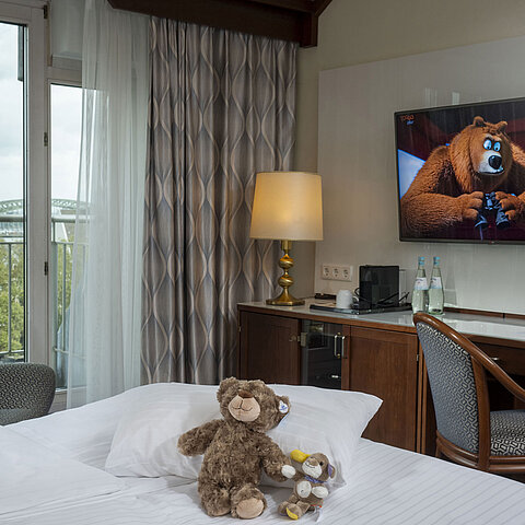 Familienzimmer im Maritim Hotel Köln mit TV, gemütlichen Kuscheltieren auf dem Bett und Blick auf den Rhein.