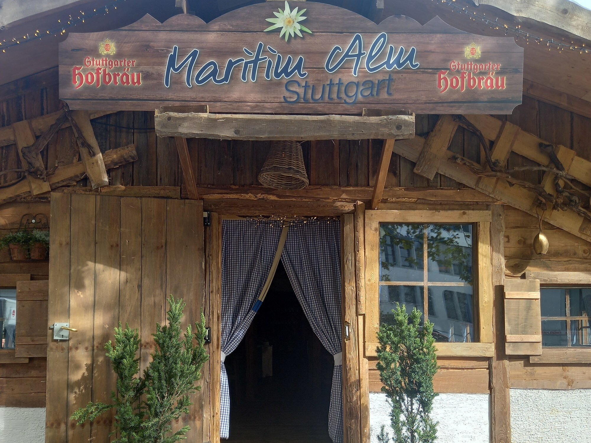 Eingang Maritim Alm Eingang mit Holzfassade und Vorhängen zur Maritim Alm neben dem Maritim Hotel Stuttgart