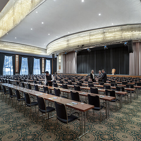 Prächtiger Saal im Maritim Hotel Magdeburg mit Bühne, Reihenbestuhlung und luxuriösem Kronleuchter.