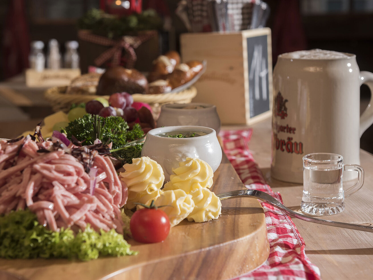 Vesperplatte Bayerischer Wurstsalat, Butterrosen, Trauben und Bierkrug auf Holzplatte in der Maritim Alm Stuttgart