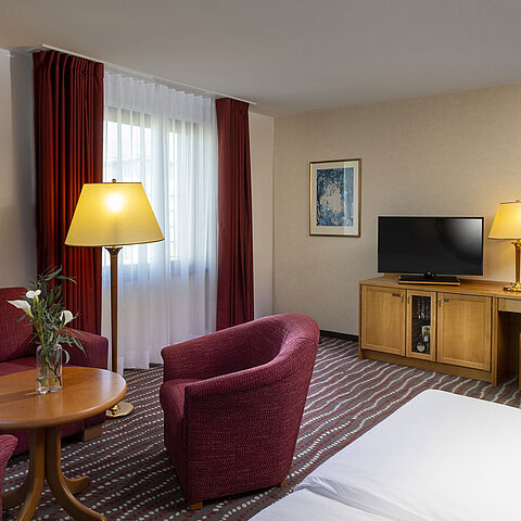 Komfortables Studiozimmer im Maritim Hotel Magdeburg mit Sitzecke, Schreibtisch und modernem TV.