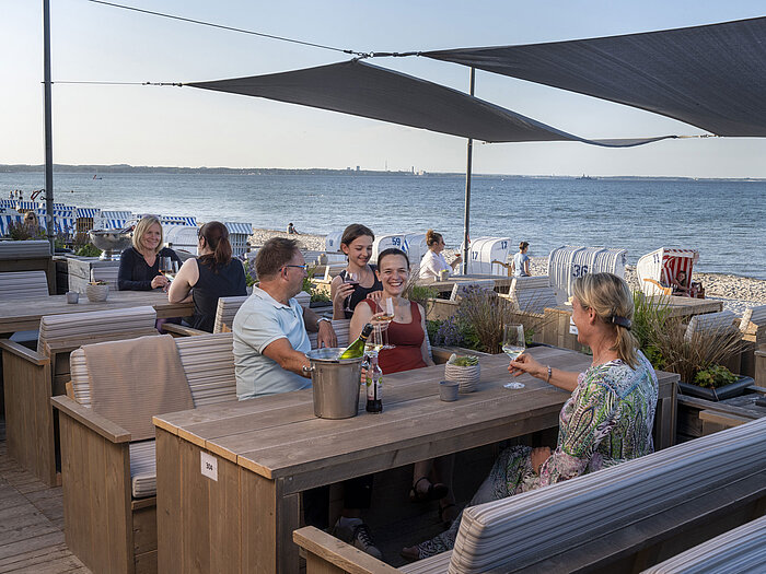 Gruppe von Gästen in der Strandbar des Maritim Seehotel Timmendorfer Strand, genießt Drinks mit Meerblick und Strandkörben.