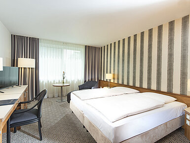 Comfort Zimmer Modernes Hotelzimmer mit gestreifter Wand, Doppelbett und Schreibtisch im Maritim Hotel Stuttgart