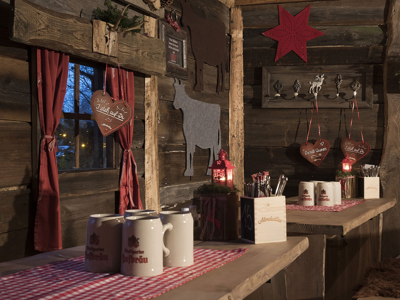 Almhütte Dekorierte Holzwand mit Filz-Kühen, Lebkuchenherzen und Kerzenlaternen in der Maritim Alm Stuttgart
