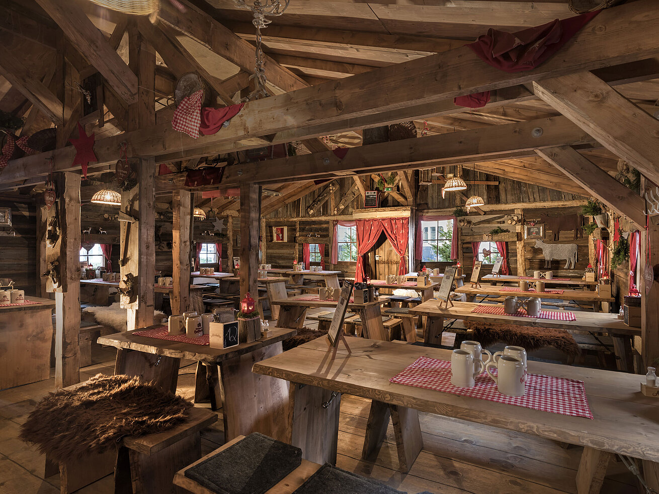 Almhütte Warmer Innenbereich mit Holztischen, roten Vorhängen und uriger Deko in der Maritim Alm Stuttgart